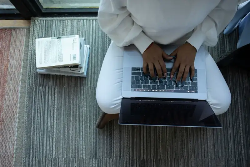 Student working on a laptop with notes beside her